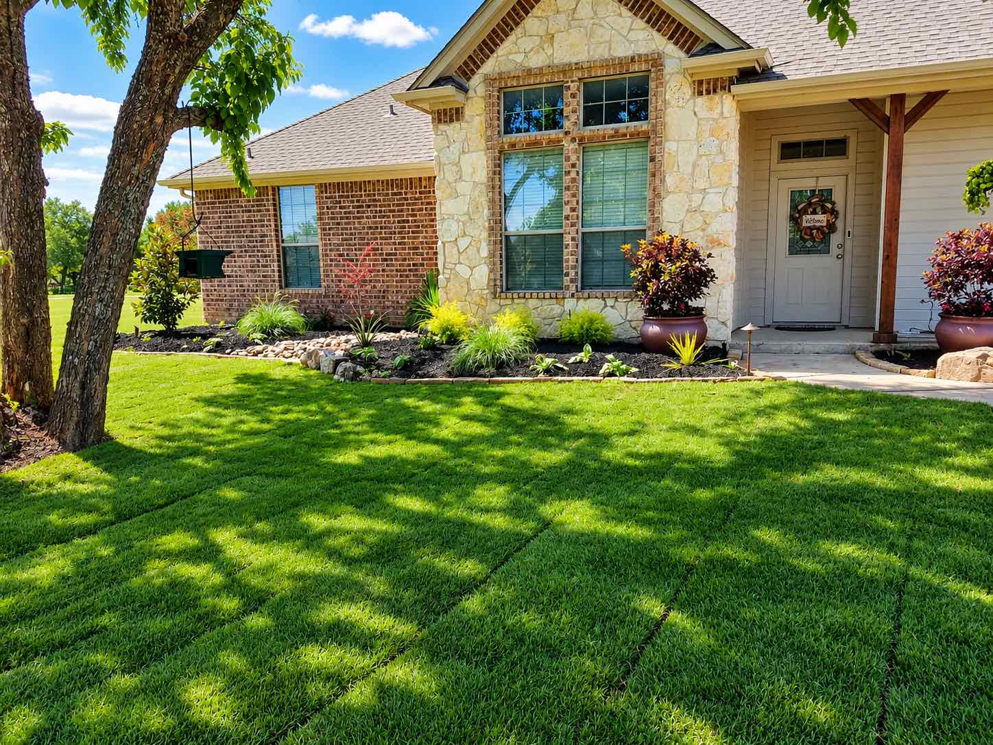 Fresh, even lawn in front of a stone and brick home